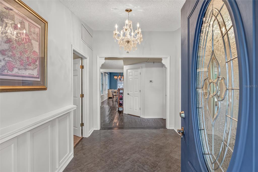 An entryway with a crystal chandelier, tiled floor, wainscoting, and a blue front door — 5927 WHITE SANDS ROAD, KEYSTONE HEIGHTS, FL