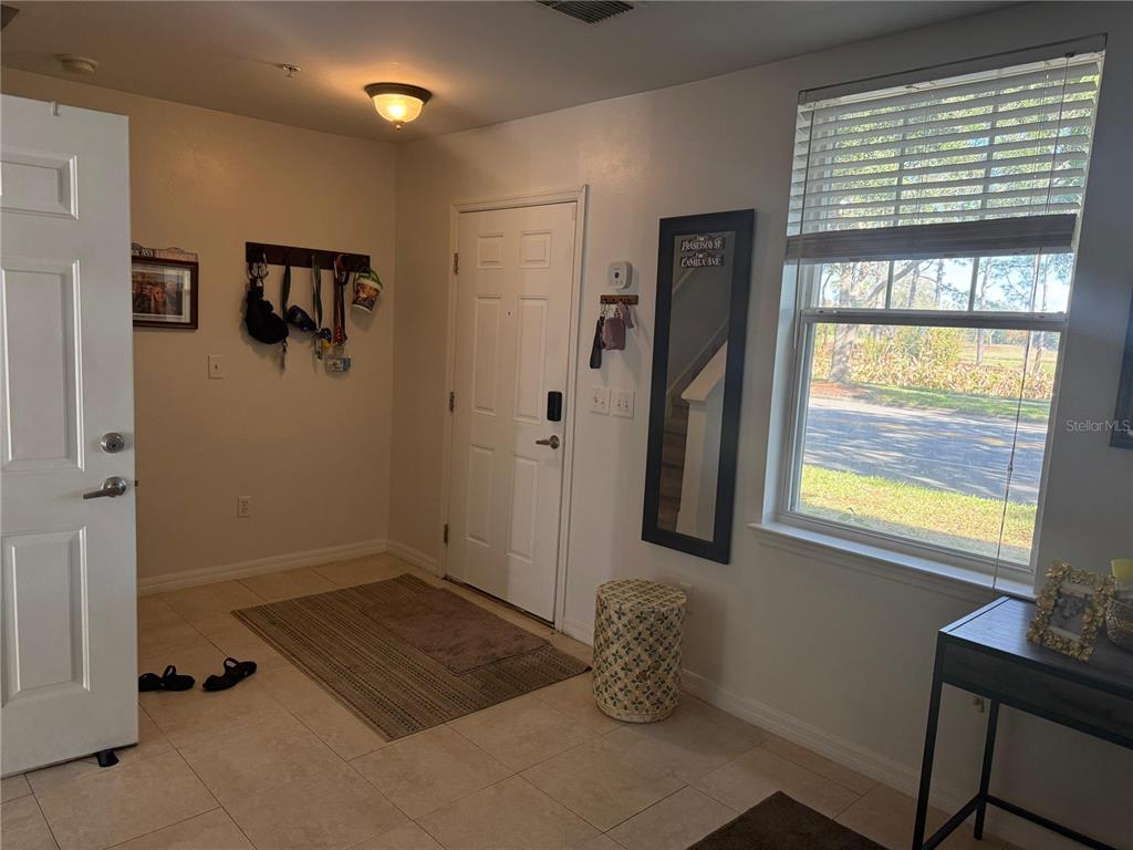 An entryway features tile flooring, a coat rack, a front door, and a window — 1004 WATERSIDE DRIVE UNIT 1004, CELEBRATION, FL