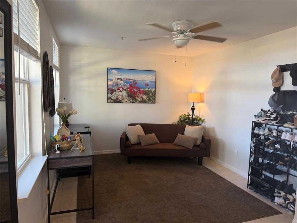 A living room features a brown sofa, a desk, a shoe rack, and a ceiling fan — 1004 WATERSIDE DRIVE UNIT 1004, CELEBRATION, FL