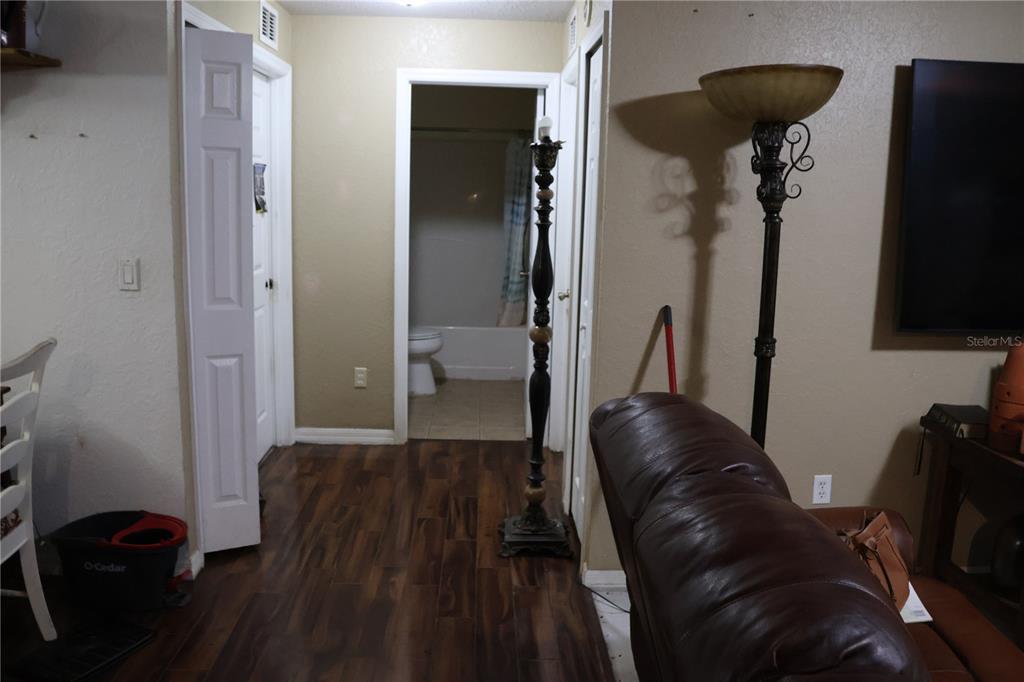 A hallway with wood-look flooring leads to a bathroom featuring a tub and toilet — 1102 REDBIRD STREET, LAKE PLACID, FL