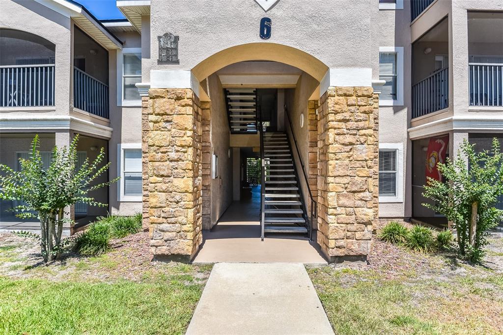 A stone-accented apartment building entrance features a central staircase leading to upper-level units — 940 VILLAGE TRAIL UNIT 6-103, PORT ORANGE, FL