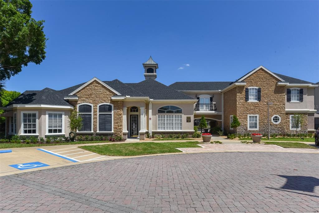 A two-story building with stone siding, a dark shingled roof, and a paved parking area — 940 VILLAGE TRAIL UNIT 6-103, PORT ORANGE, FL