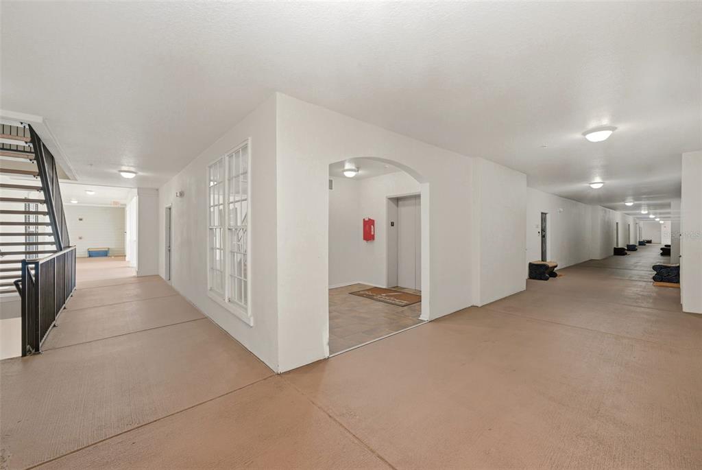 An outdoor apartment building hallway features a staircase, an elevator entrance, and a long walkway — 239 LONGVIEW AVENUE UNIT 207, CELEBRATION, FL