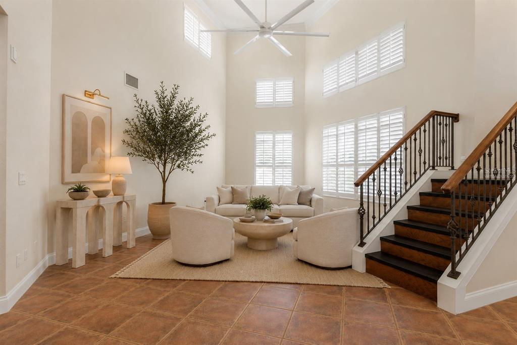 A living room with high ceilings, a staircase, tile flooring, and neutral-toned furniture — 6 MONTERREY DRIVE, PALM COAST, FL