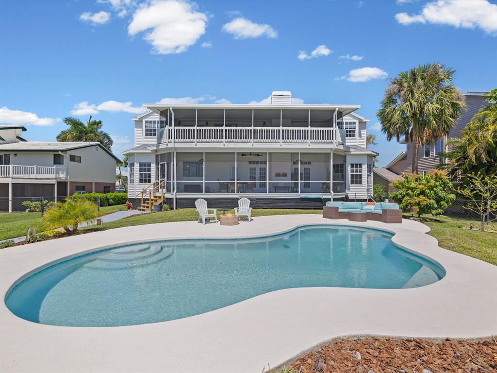 A two-story house with a screened-in porch and balcony overlooks a kidney-shaped swimming pool — 1414 DEIRDRE DRIVE, RUSKIN, FL