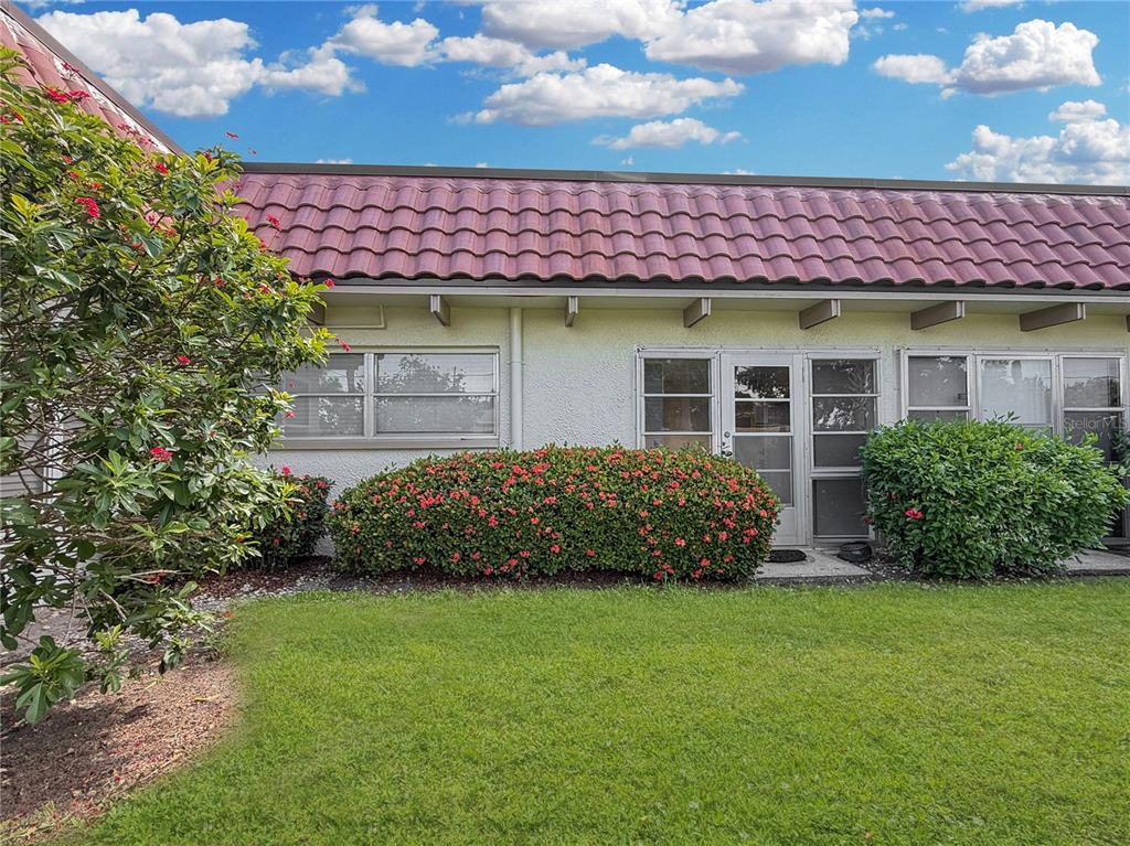 A single-story building with a red tile roof, white stucco walls, and a landscaped lawn — 1701 PINEHURST ROAD UNIT 2F, DUNEDIN, FL