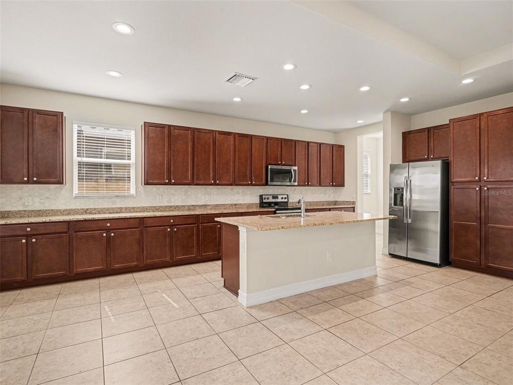 A spacious kitchen and living area with tile floors, dark wood cabinets, and sliding glass doors — 4429 CONCHFISH LANE, OSPREY, FL