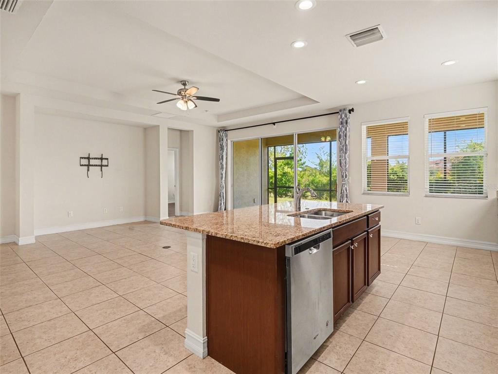 A kitchen features dark wood cabinets, granite countertops, stainless steel appliances, and tile flooring — 4429 CONCHFISH LANE, OSPREY, FL