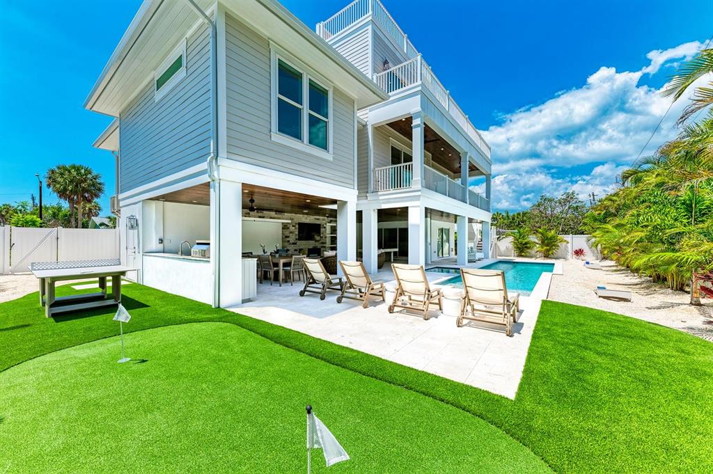 A multi-story house with a backyard pool, putting green, covered patio, and outdoor kitchen — 215 83RD STREET, HOLMES BEACH, FL