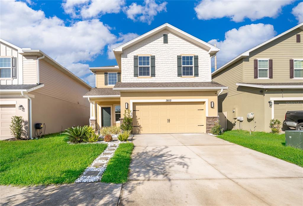 A two-story suburban house features a tan garage, white siding, and a concrete driveway — 3852 SAGEFIELD DRIVE, HARMONY, FL