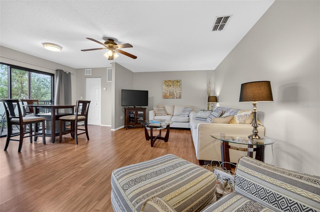 A hallway with wood-look flooring, mirrored closet doors, and a doorway leading to a kitchen — 6080 80TH STREET N UNIT 409, ST PETERSBURG, FL