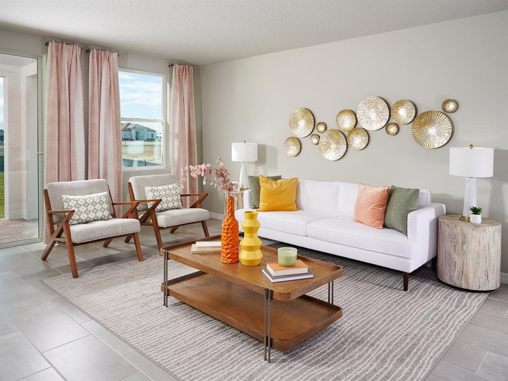 A living room features a white sofa, two armchairs, a wooden coffee table, and wall decor — 646 PENNYWORT STREET, LAKE ALFRED, FL