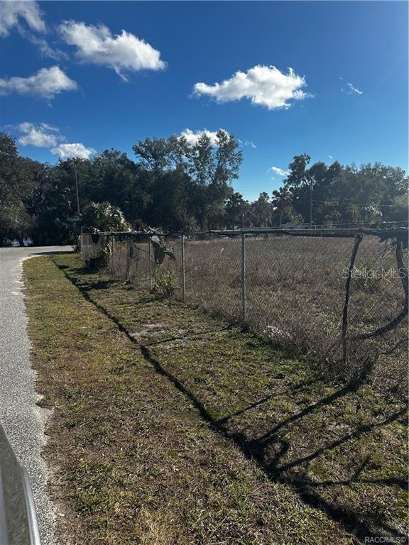 A chain-link fence borders a vacant, grassy lot under a blue sky with scattered clouds — 3172 N AQUAVIEW TERRACE, HERNANDO, FL