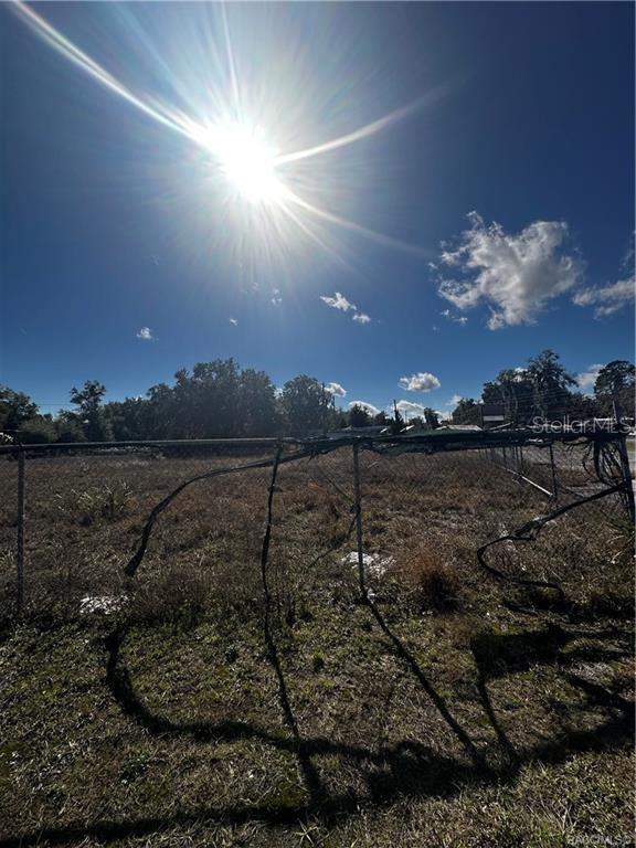 A chain-link fence borders a dry, grassy lot under a bright, sunny sky — 3172 N AQUAVIEW TERRACE, HERNANDO, FL