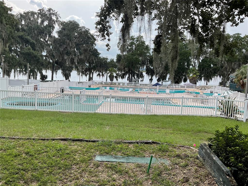 A white fenced pool area overlooks a lake surrounded by trees with Spanish moss — 25289 NE 140TH LANE NE UNIT 363, SALT SPRINGS, FL