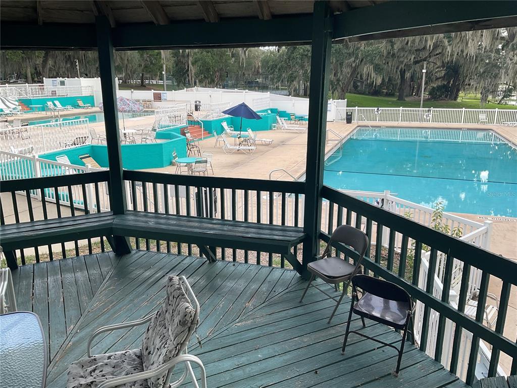 A covered wooden gazebo deck overlooks a swimming pool area with lounge chairs and umbrellas — 25289 NE 140TH LANE NE UNIT 363, SALT SPRINGS, FL