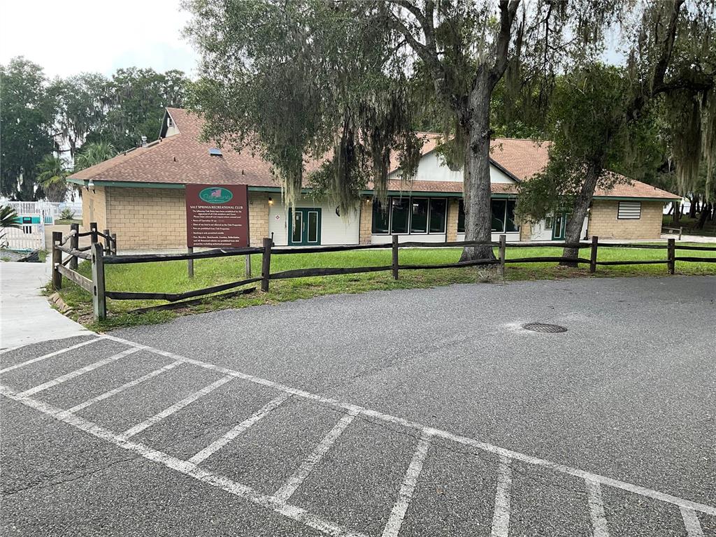 A single-story building with a brown roof sits behind a wooden fence and parking lot — 25289 NE 140TH LANE NE UNIT 363, SALT SPRINGS, FL