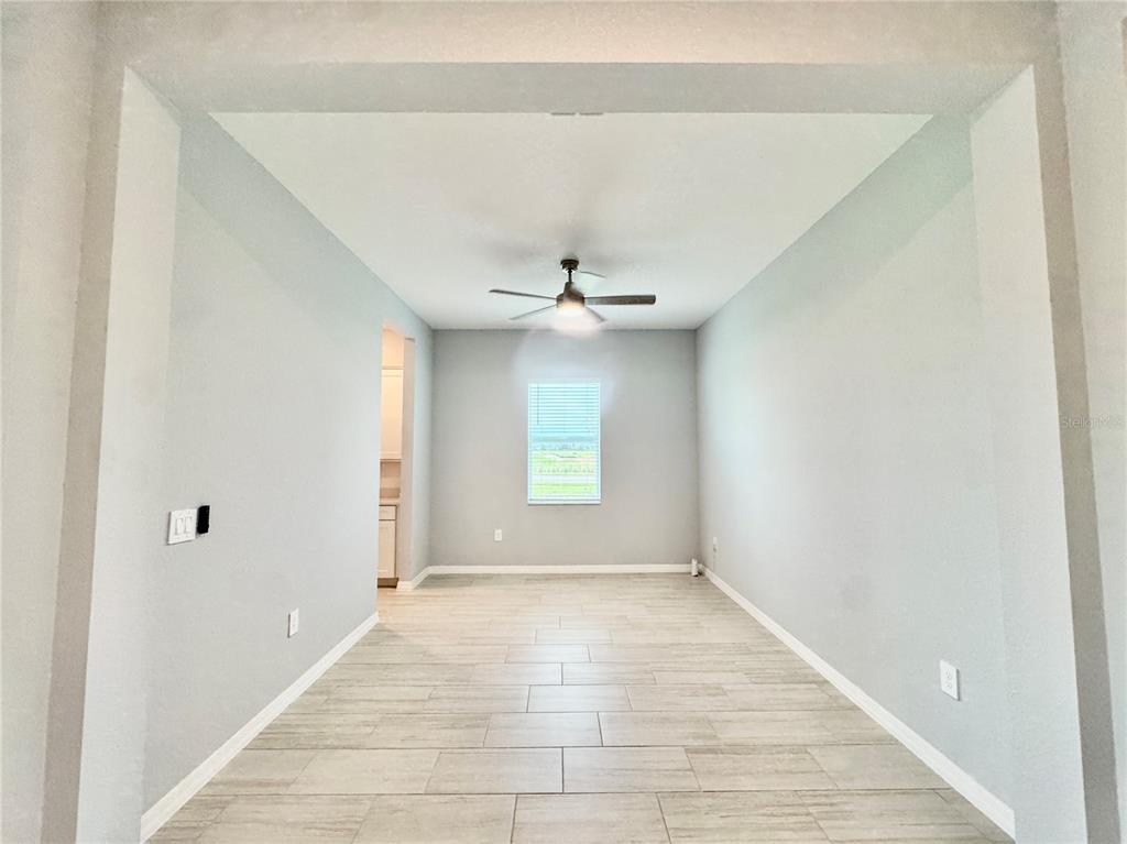 An empty room with light gray walls, tile flooring, a ceiling fan, and a window — 19227 SCALLOP LOOP, LAKEWOOD RANCH, FL