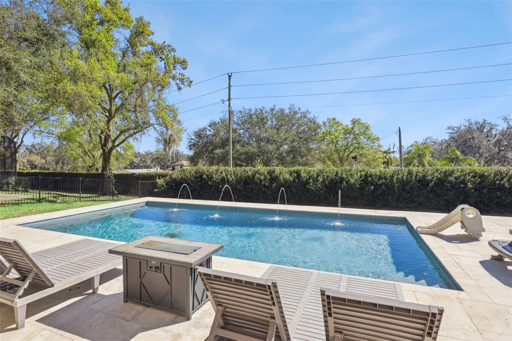 A rectangular swimming pool with water jets sits on a patio with lounge chairs — 11526 OSPREY POINTE BOULEVARD, CLERMONT, FL