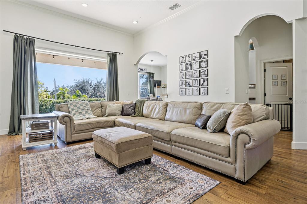 A living room features a large sectional sofa, an ottoman, and a patterned area rug — 11526 OSPREY POINTE BOULEVARD, CLERMONT, FL