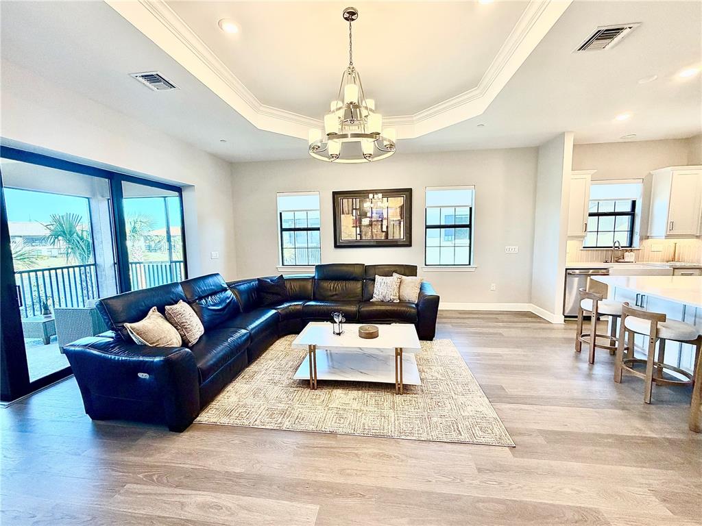 A living room features a black sectional sofa, a white coffee table, and a chandelier — 15323 LUCERNA STREET UNIT 204, NAPLES, FL