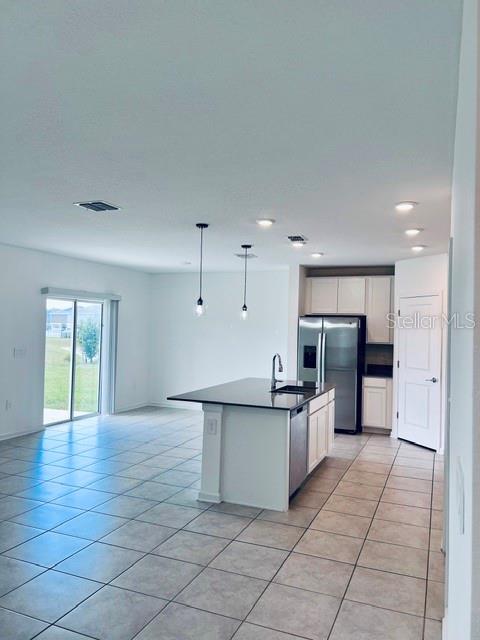 A kitchen with a center island and stainless steel appliances opens to a living area — 865 DARING DRIVE, DAVENPORT, FL