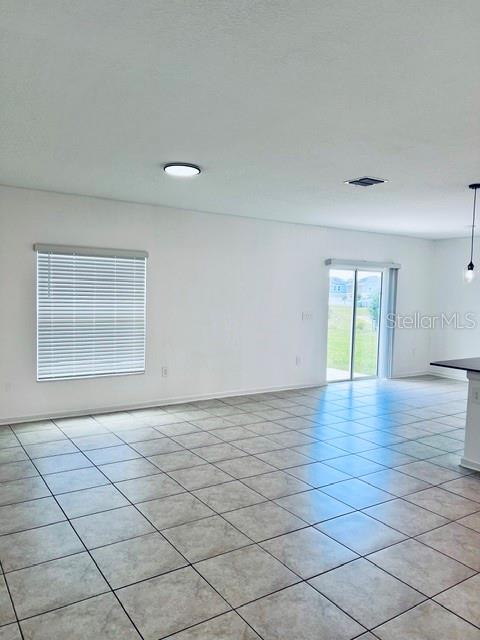 An open-concept room features light-colored tile flooring, a window with blinds, and a sliding glass door — 865 DARING DRIVE, DAVENPORT, FL