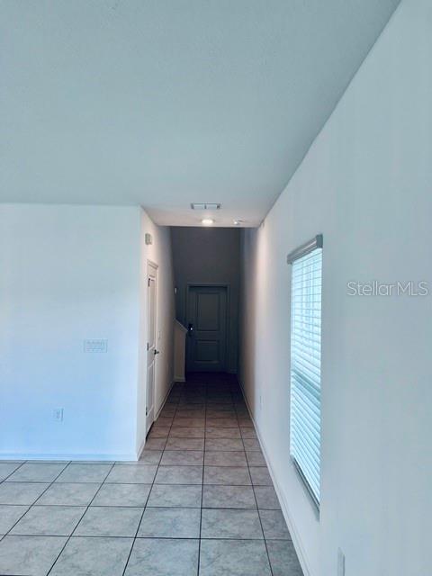 A hallway with tiled flooring leads to a closed door under a recessed ceiling light — 865 DARING DRIVE, DAVENPORT, FL