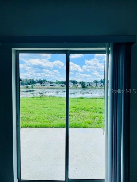 A sliding glass door looks out onto a concrete patio, grassy yard, and a pond — 865 DARING DRIVE, DAVENPORT, FL