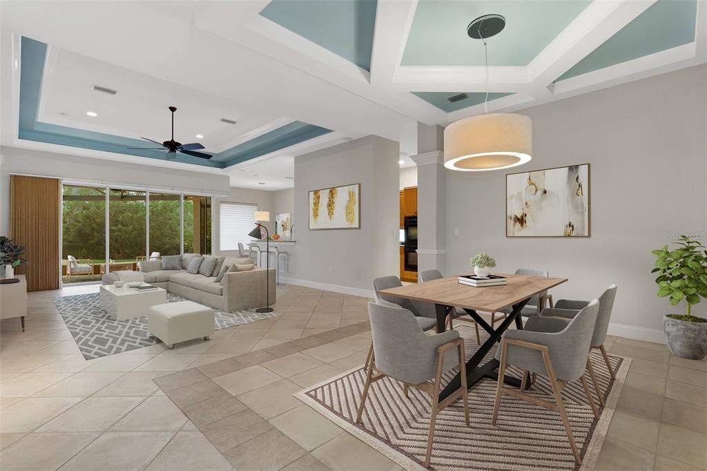 An open-concept living and dining area features tray ceilings, tile flooring, and sliding glass doors — 299 TURQUOISE LANE, OSPREY, FL