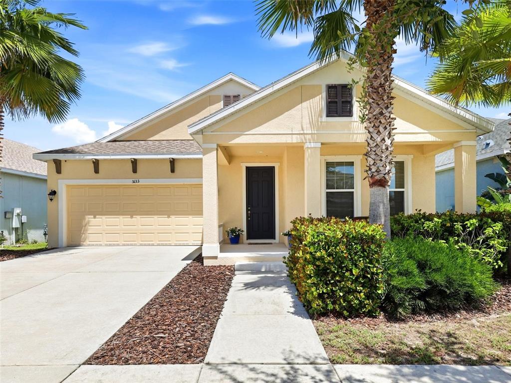 A single-story house with a yellow stucco exterior, a two-car garage, and a palm tree — 5133 ADMIRAL POINTE DRIVE, APOLLO BEACH, FL