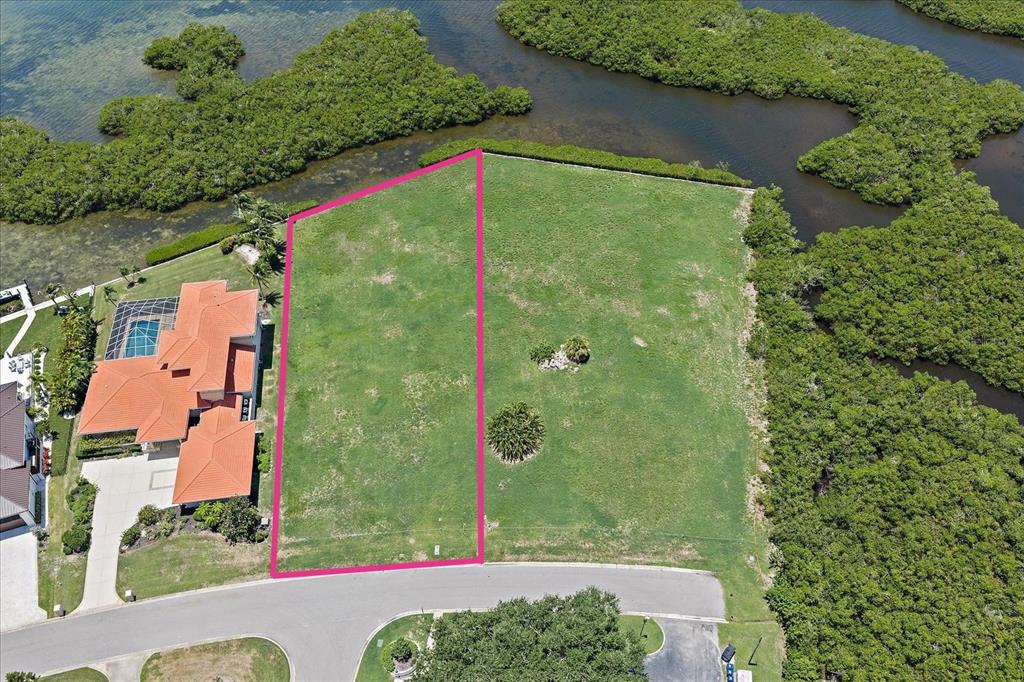 An aerial view shows a vacant, grassy residential lot outlined in pink next to a house — TIDEWOOD AVENUE, SARASOTA, FL