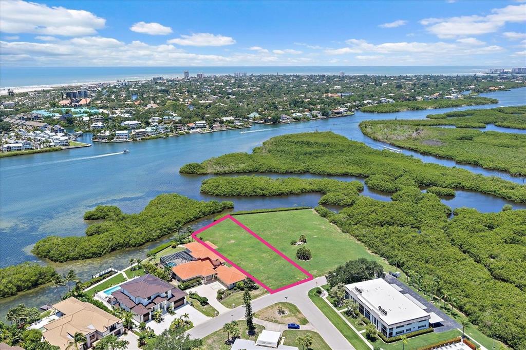 An aerial view shows a vacant rectangular lot outlined in pink near a coastal waterway — TIDEWOOD AVENUE, SARASOTA, FL