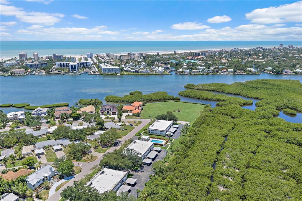 An aerial view shows a coastal neighborhood with houses, apartment buildings, and dense mangrove vegetation — TIDEWOOD AVENUE, SARASOTA, FL