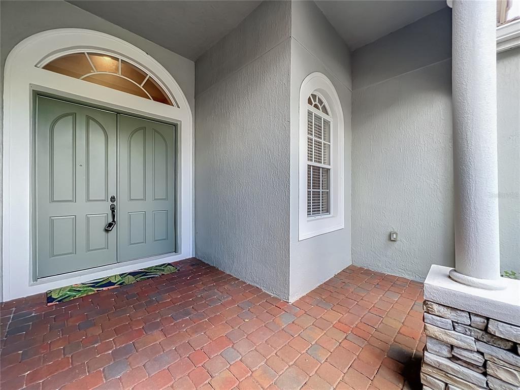 A covered porch features a brick floor, a light green double door, and a stone column — 2139 TILLMAN AVENUE, WINTER GARDEN, FL
