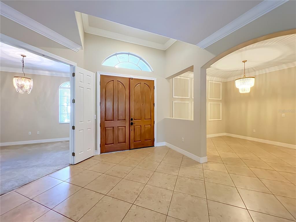 A tiled foyer features double wood front doors, a transom window, and two adjacent rooms — 2139 TILLMAN AVENUE, WINTER GARDEN, FL