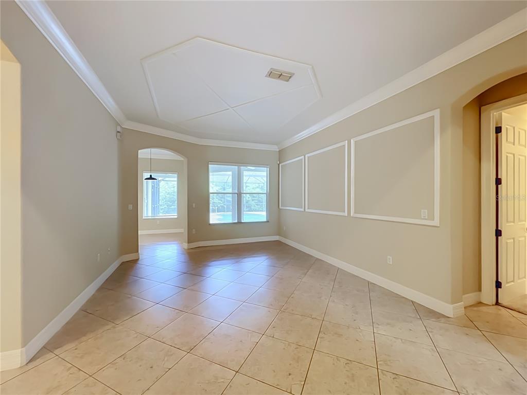 A bright, empty room features beige walls with wainscoting, tile flooring, and a tray ceiling — 2139 TILLMAN AVENUE, WINTER GARDEN, FL