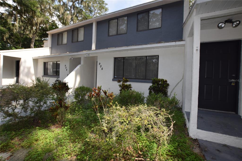 A two-story townhouse exterior with white stucco, dark blue siding, and a landscaped front yard — 908 SUMTER STREET, LEESBURG, FL