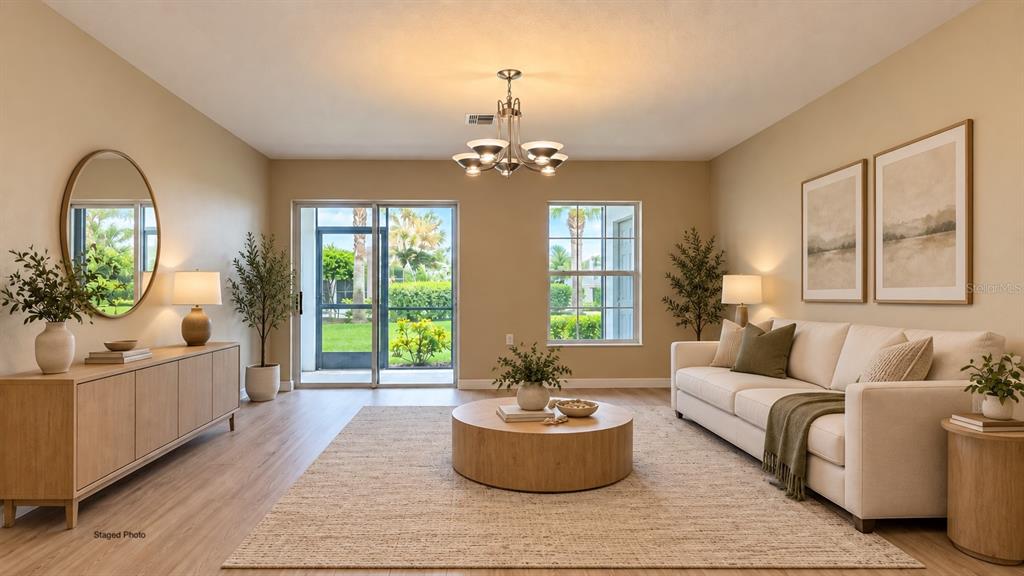 This staged living room features a beige sofa, wooden coffee table, and sliding glass doors — 9063 GERVAIS CIRCLE UNIT 1204, NAPLES, FL