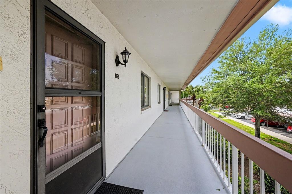 An exterior walkway with a white railing overlooks a parking area and trees — 172 LAKEVIEW WAY UNIT 172, OLDSMAR, FL