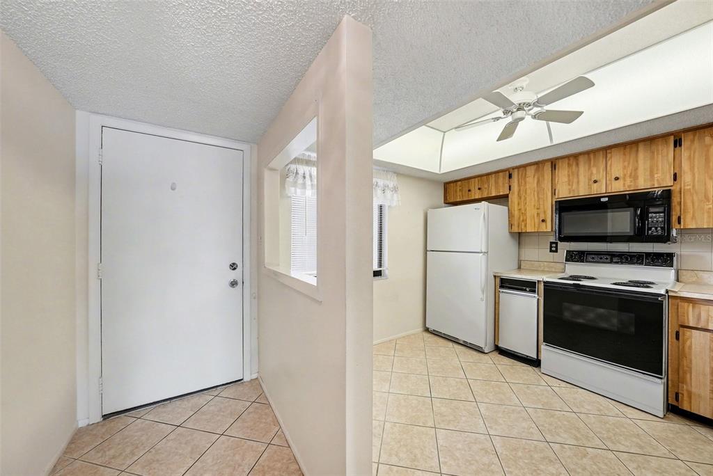 A kitchen with light-colored tile floors, wooden cabinets, and a white refrigerator and stove — 172 LAKEVIEW WAY UNIT 172, OLDSMAR, FL