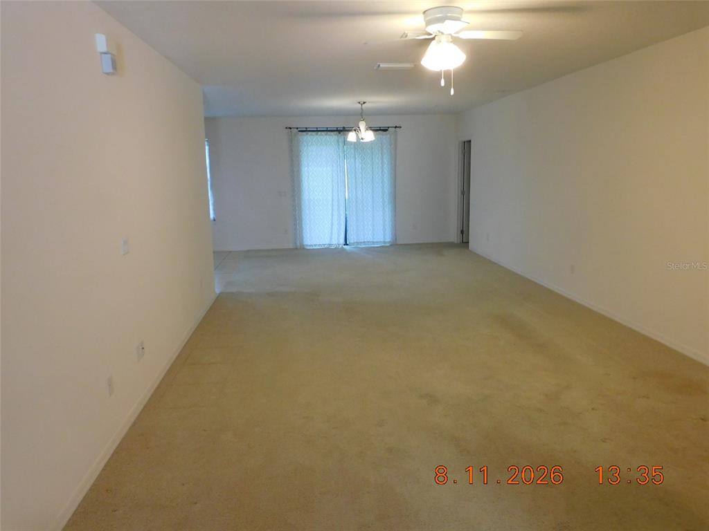An empty room with beige carpeting, white walls, a ceiling fan, and sliding glass doors — 2916 CASABELLA DRIVE, KISSIMMEE, FL