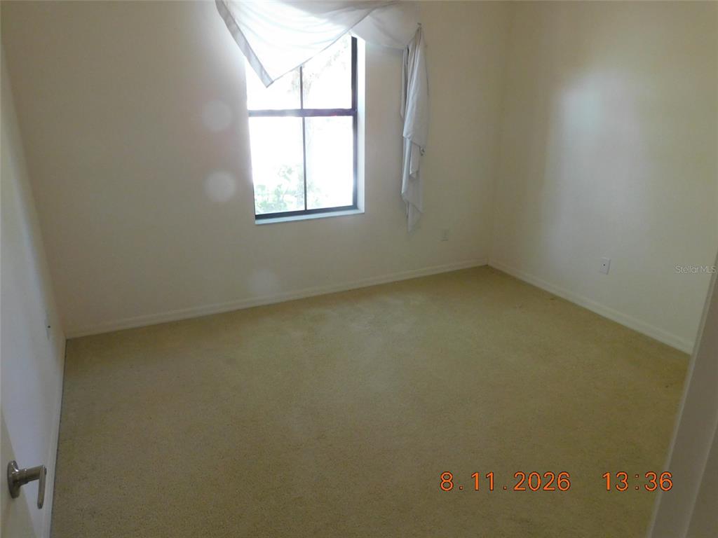 An empty bedroom features beige carpeting, off-white walls, and a single window with white curtains — 2916 CASABELLA DRIVE, KISSIMMEE, FL