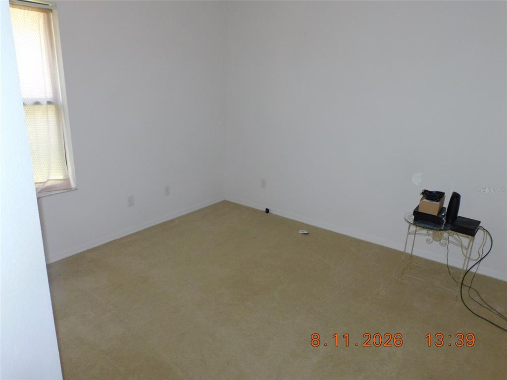 An empty bedroom features beige carpeting, white walls, and a window with a sheer curtain — 2916 CASABELLA DRIVE, KISSIMMEE, FL