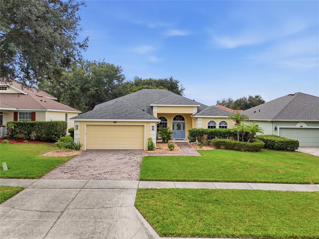A single-story house with a yellow stucco exterior, a two-car garage, and a paved driveway — 3790 LIBERTY HILL DRIVE, CLERMONT, FL