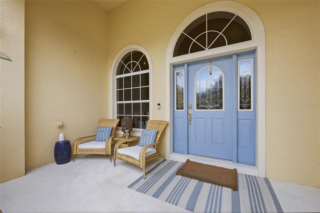 A light blue front door with glass inserts sits beside two wicker chairs on a porch — 3790 LIBERTY HILL DRIVE, CLERMONT, FL