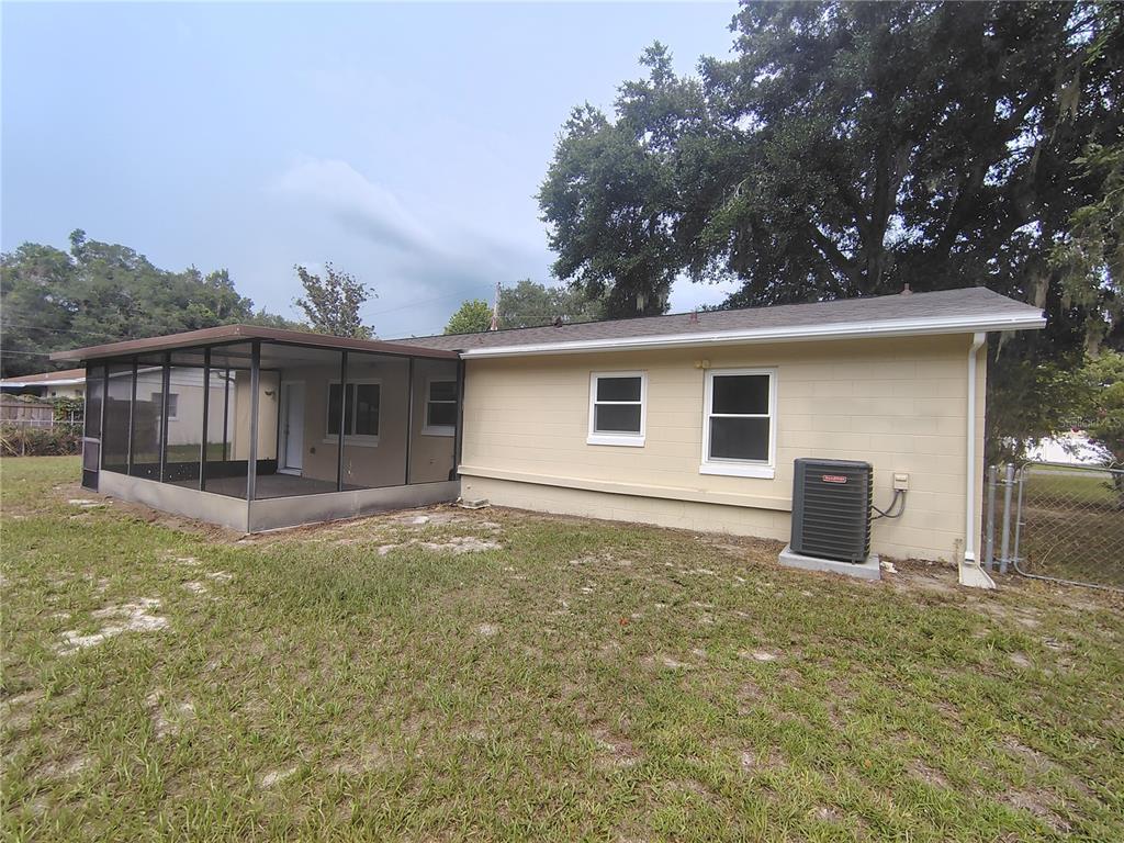 The exterior of a single-story house features a screened-in porch and a central air conditioning unit — 904 HICKORY AVENUE, FRUITLAND PARK, FL
