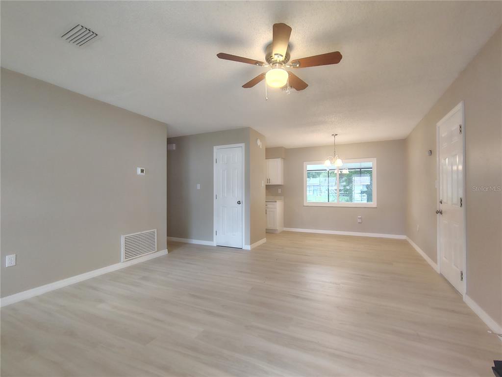 An open-concept living and dining area features light wood-look flooring and a ceiling fan — 904 HICKORY AVENUE, FRUITLAND PARK, FL