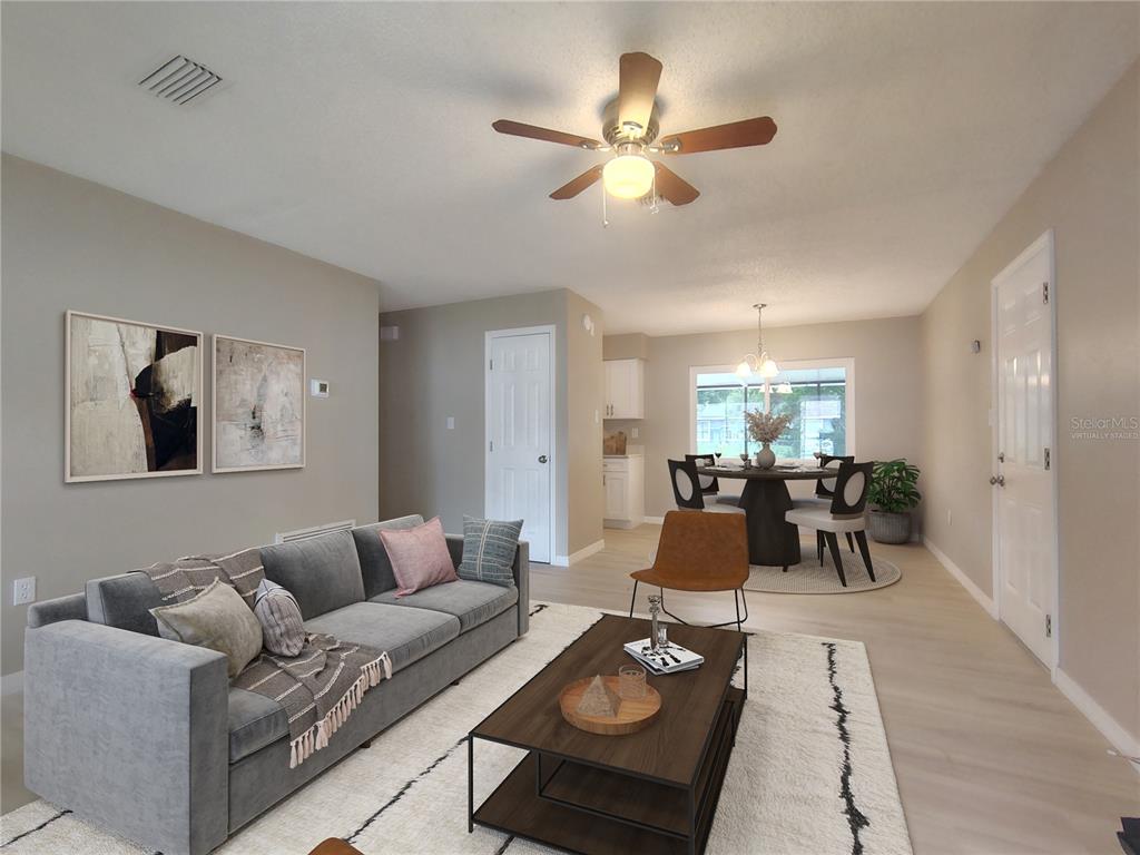 A living room with a grey sofa, coffee table, and an adjacent dining area — 904 HICKORY AVENUE, FRUITLAND PARK, FL