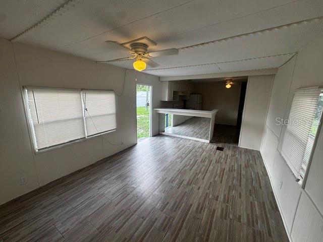 A living room with wood-look tile flooring, a ceiling fan, and a breakfast bar — 7205 COMMONS BOULEVARD, PORT RICHEY, FL